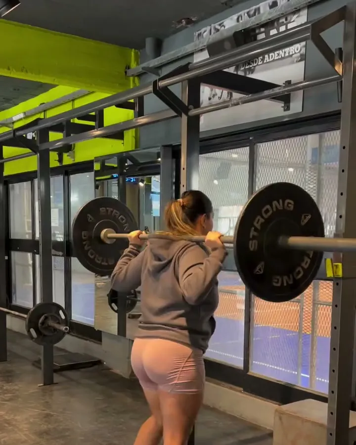 Socia entrenando con barra bajo supervisión del profe