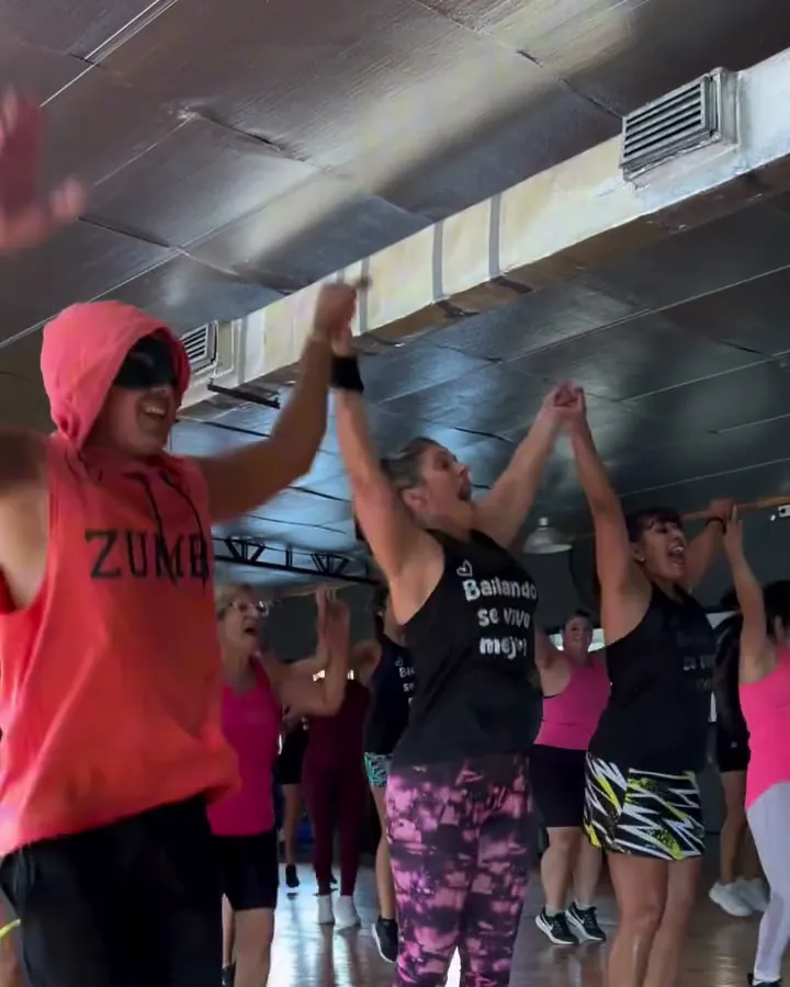 Clase de Zumba con el salón lleno y las manos arriba